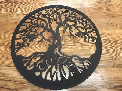 A black tree of life is sitting on a wooden table.