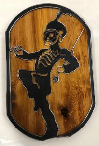 A wooden plaque with a skeleton marching band member on it.