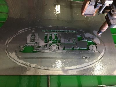 A machine is cutting a piece of metal with a picture of a truck on it.