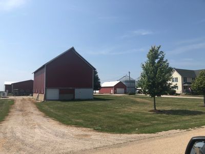 A red barn is sitting in the middle of a grassy field.