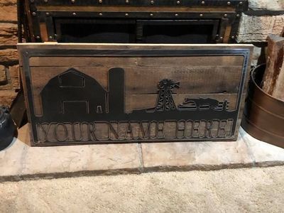 A wooden sign with a barn and a windmill on it is sitting on top of a fireplace.