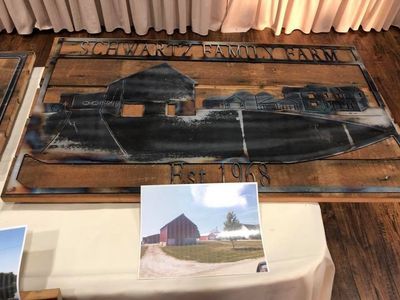 A painting of a barn is on a wooden table.