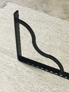 A black metal shelf bracket is sitting on top of a table.