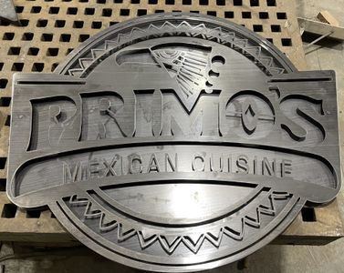 A metal sign for primo 's mexican cuisine is sitting on top of a wooden table.