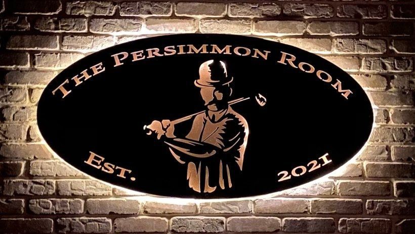 A sign on a brick wall that says the persimmon room