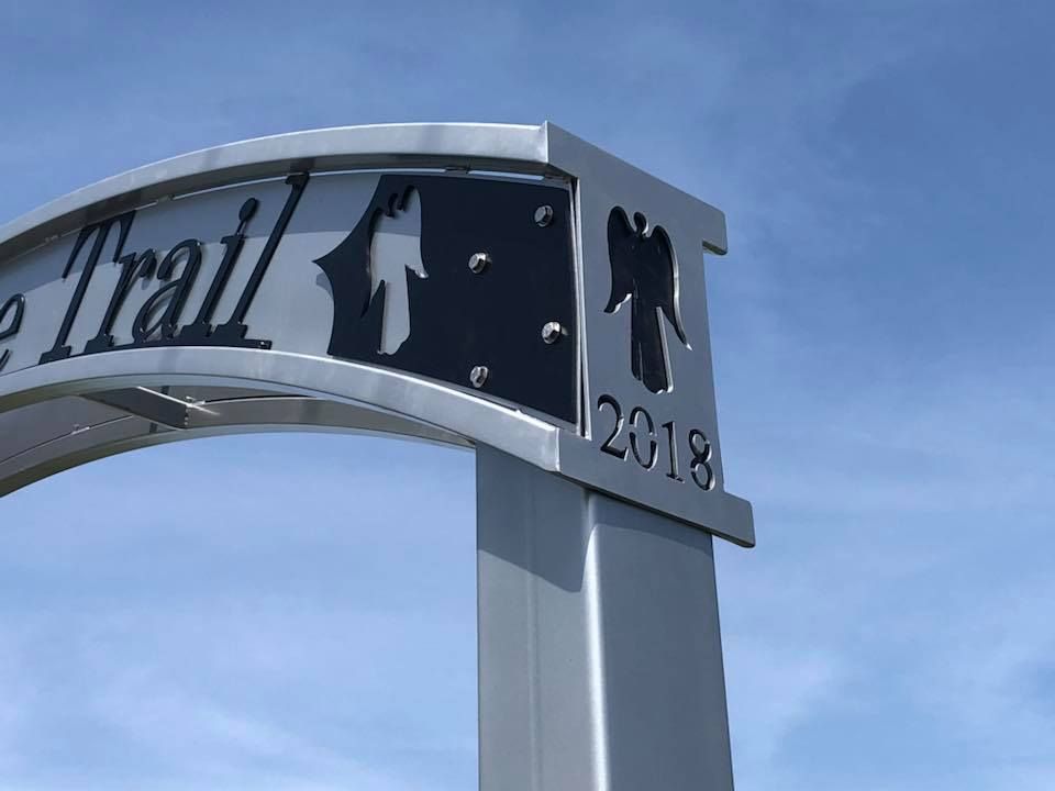 A sign for the trail is against a blue sky