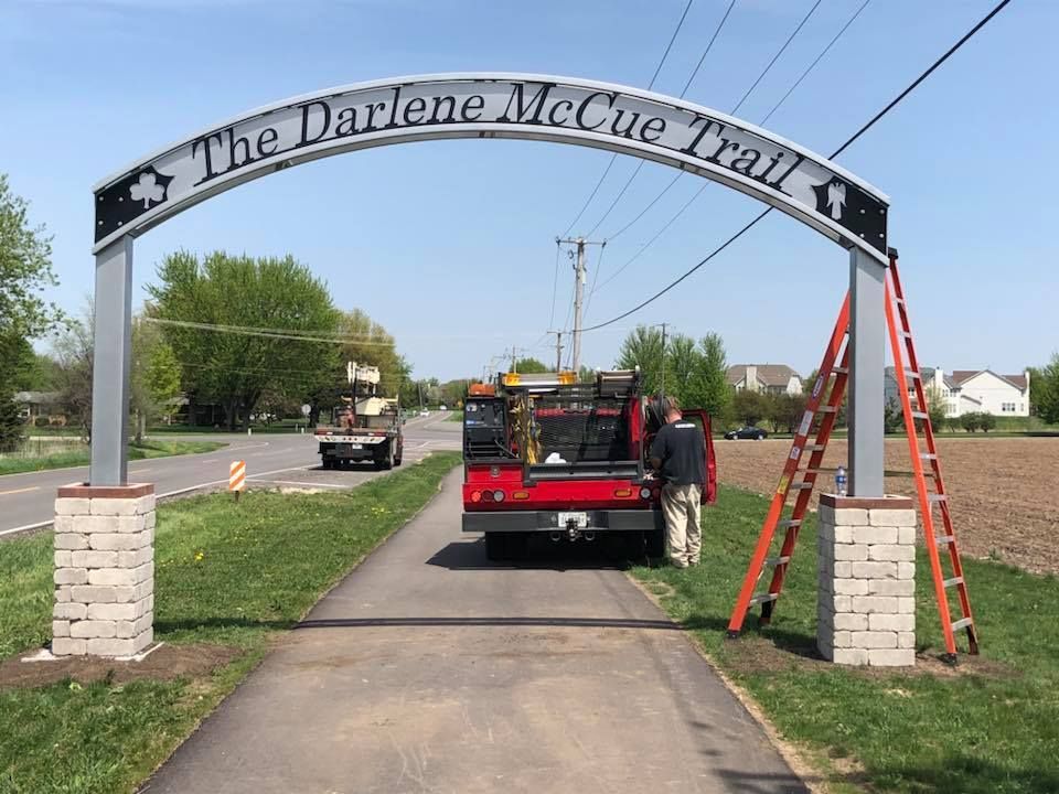 A truck is parked under a sign that says the darlene mccue trail