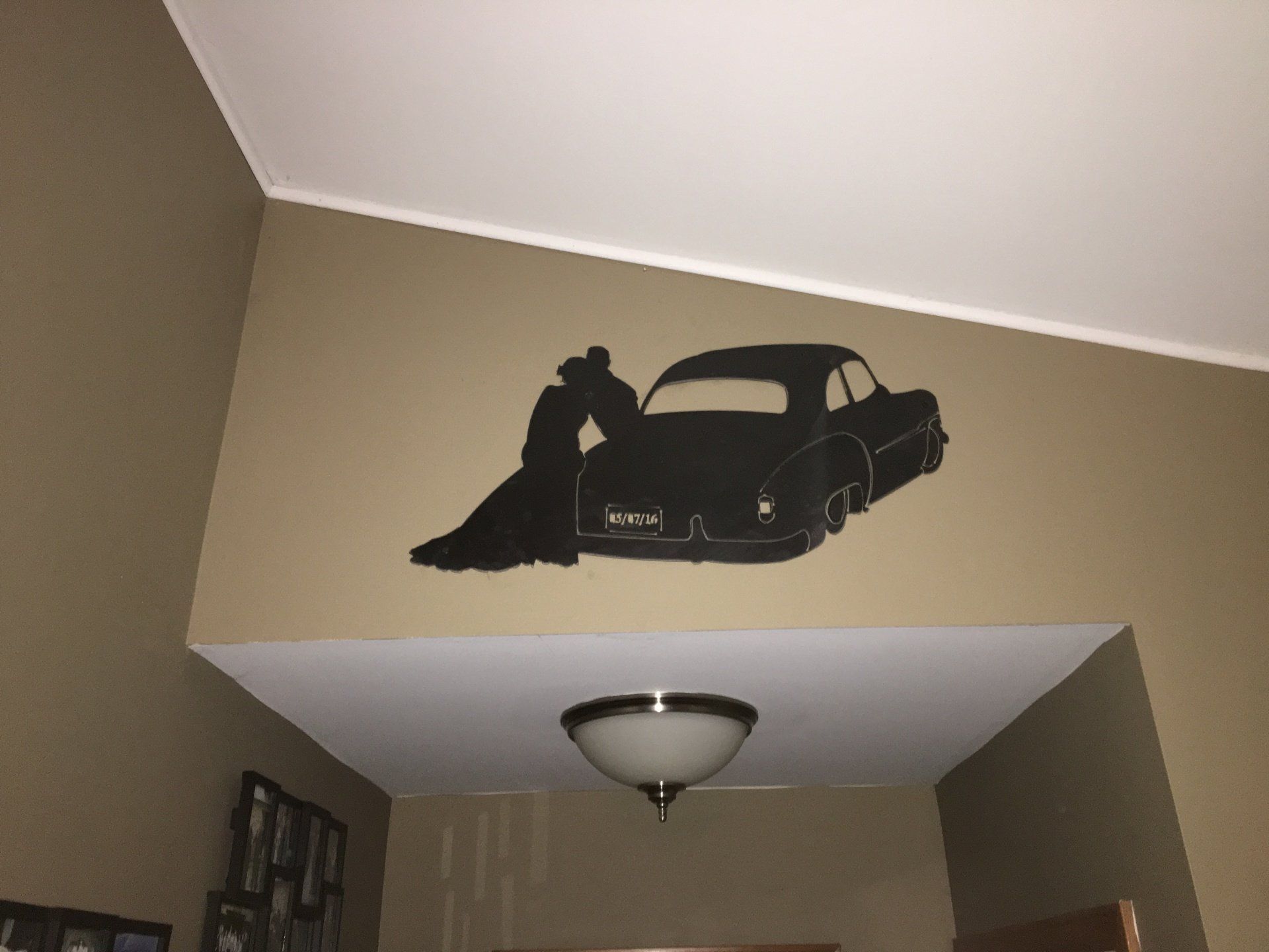 A silhouette of a man standing next to a car on a wall