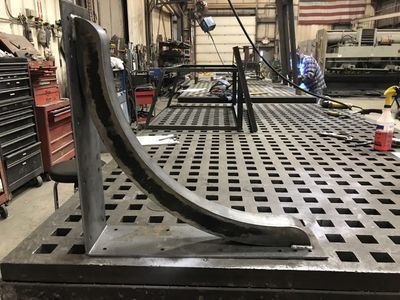 A metal bracket is sitting on top of a metal table.