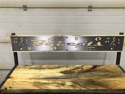 A wooden bench with a metal sign on it.