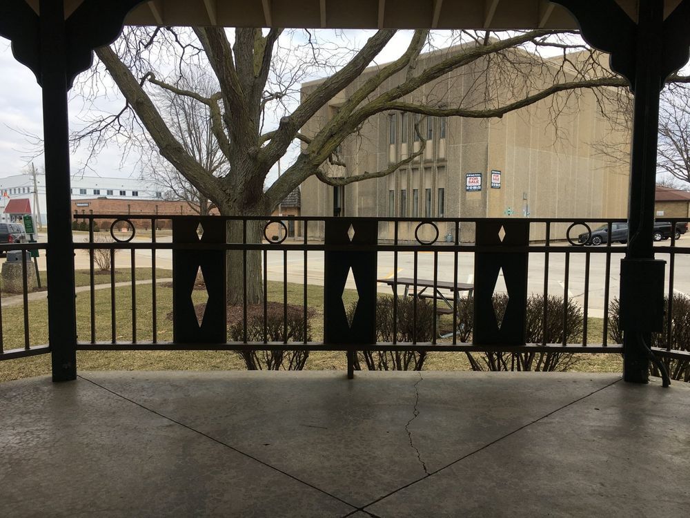A gazebo with a fence and a tree in the background