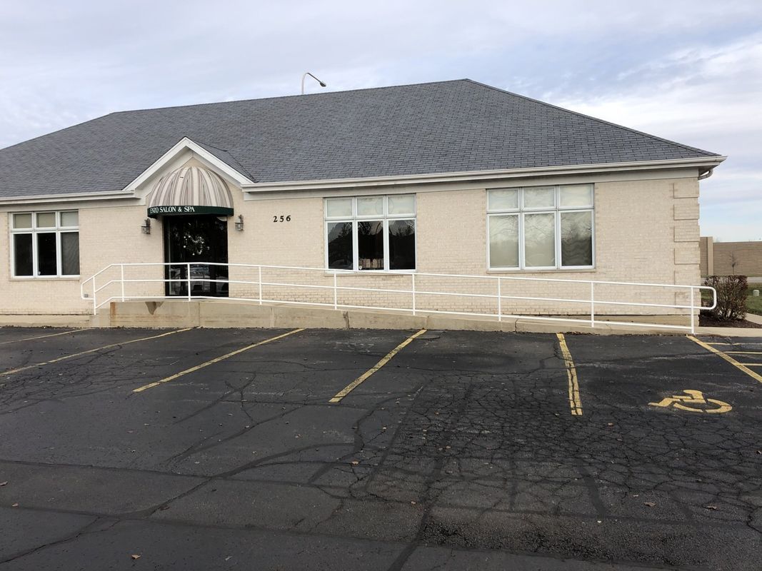 A large white building with a handicapped parking spot in front of it.