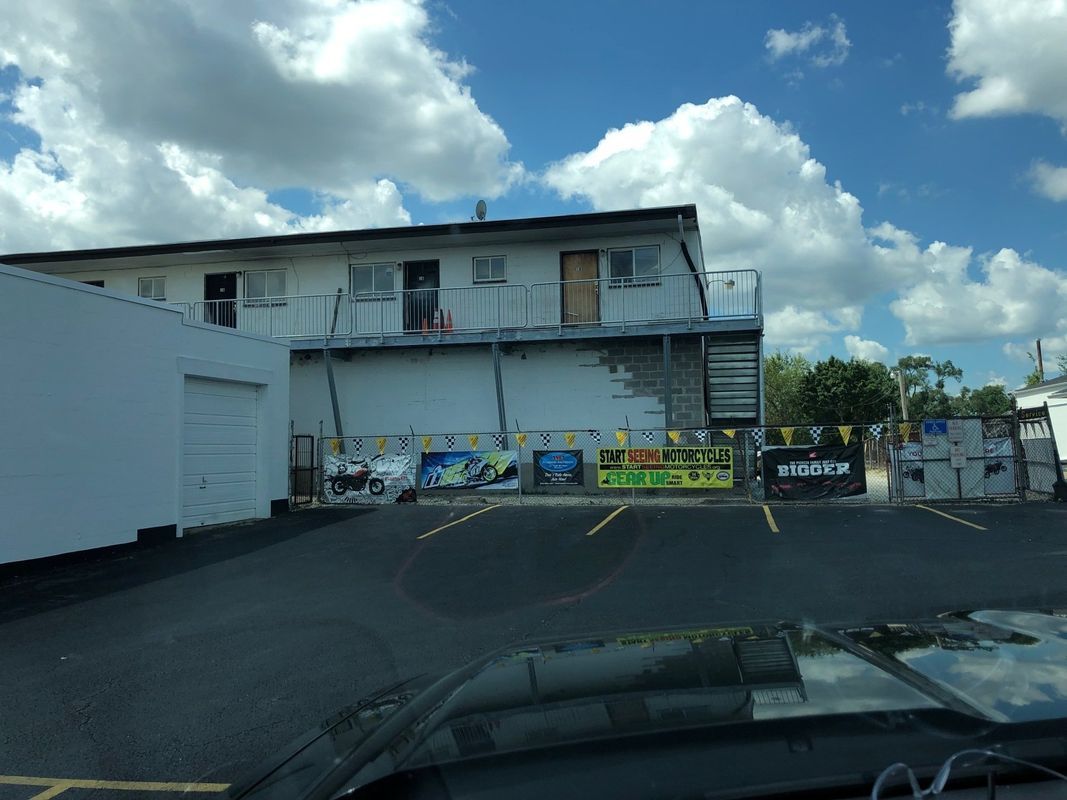 A building with graffiti on the side of it and a parking lot in front of it.