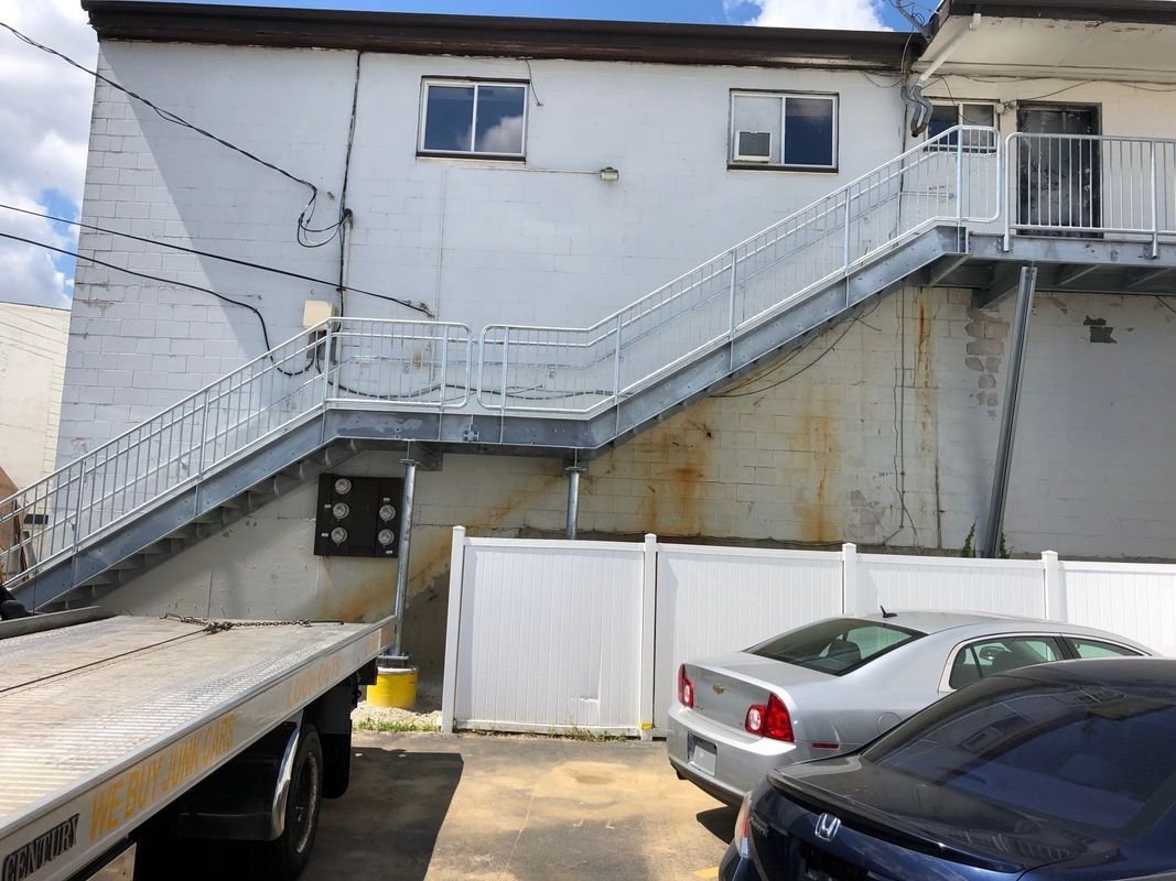 A tow truck is parked in front of a building with stairs leading up to it.