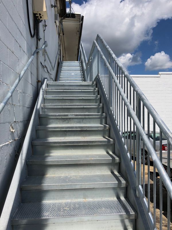 A set of stairs leading up to a building with a metal railing.