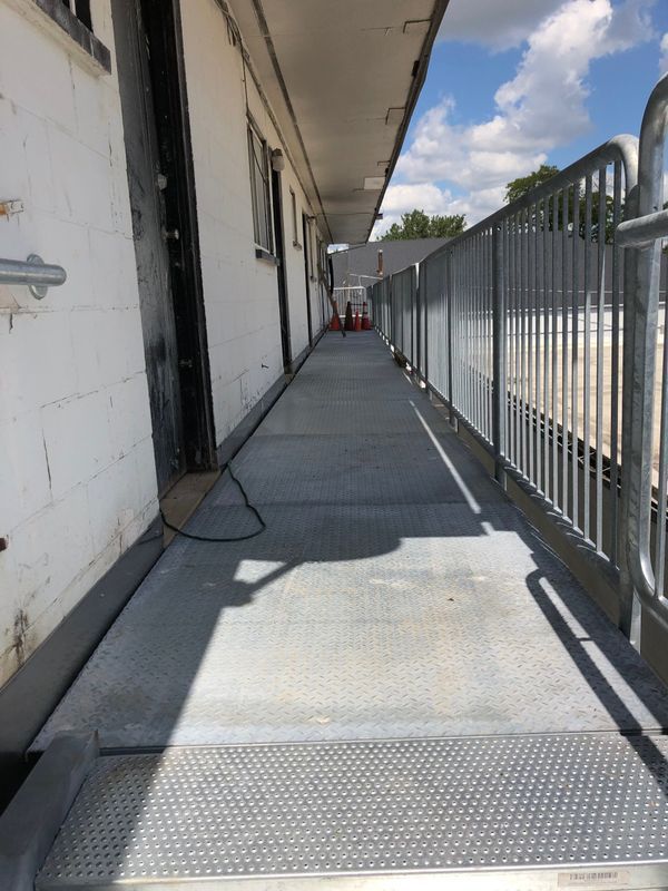 A long hallway between two buildings with a metal railing