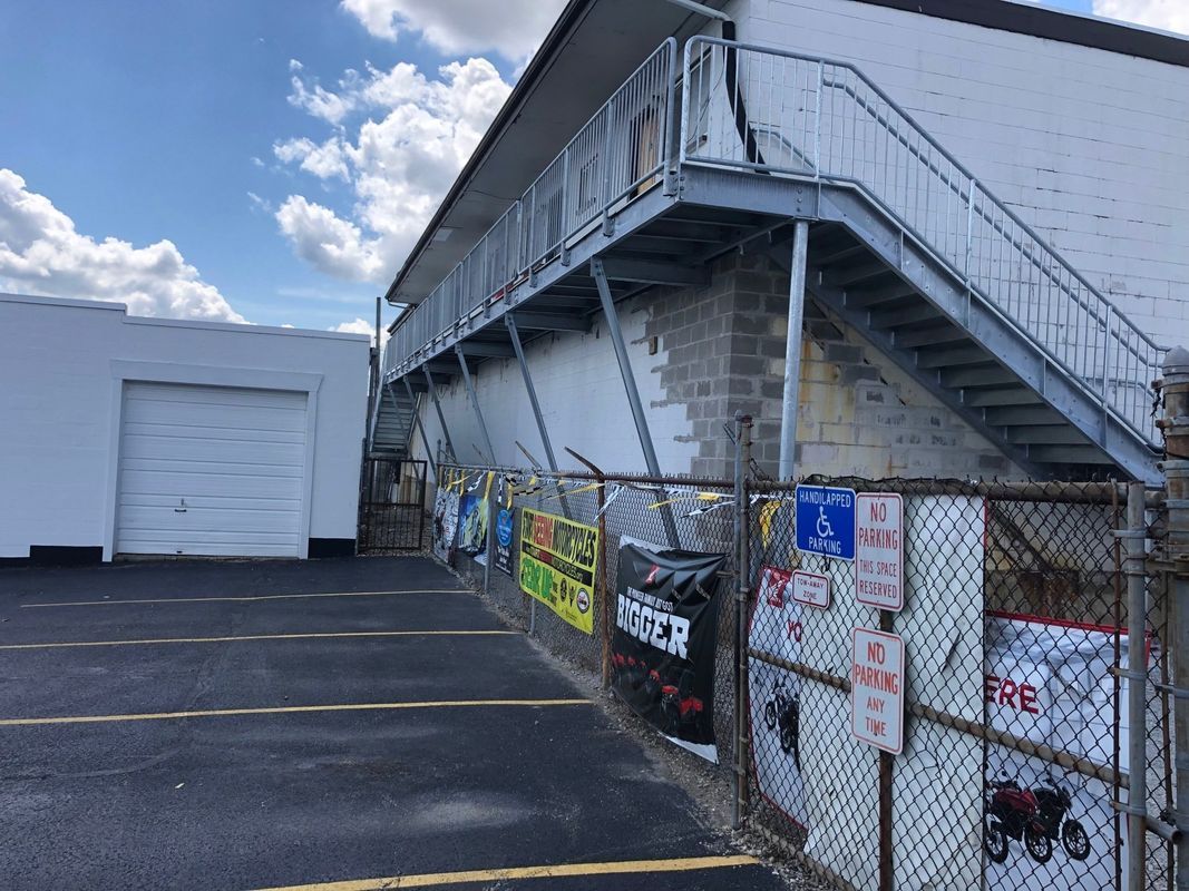 A white building with stairs leading up to the second floor