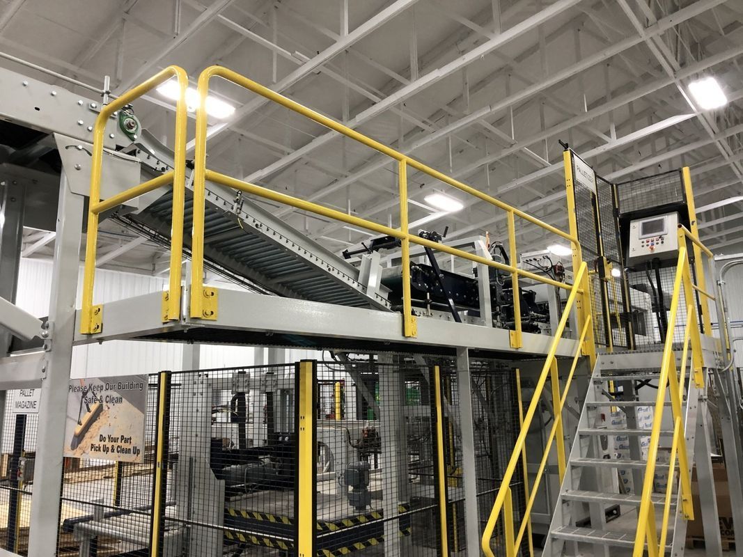 A machine in a factory with a yellow railing and stairs.