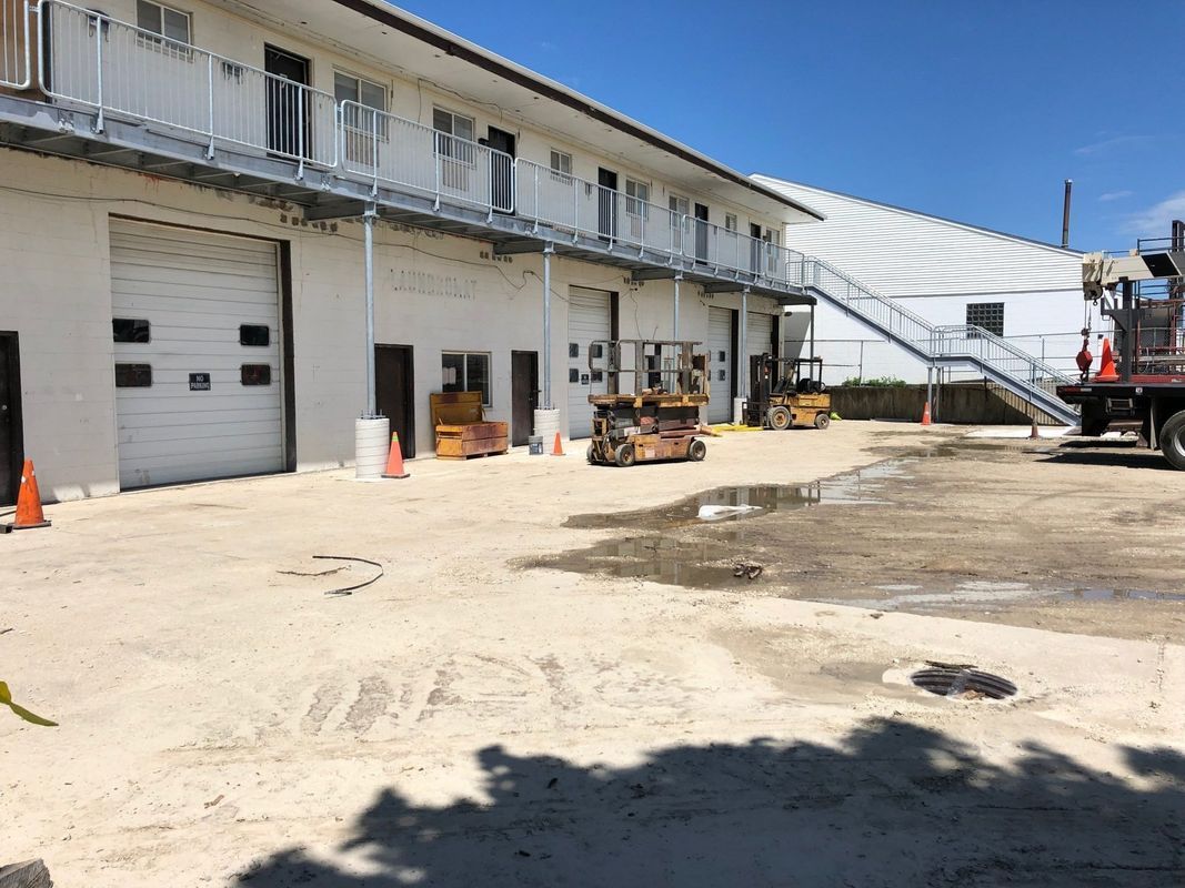 A large white building with stairs and a truck parked in front of it.