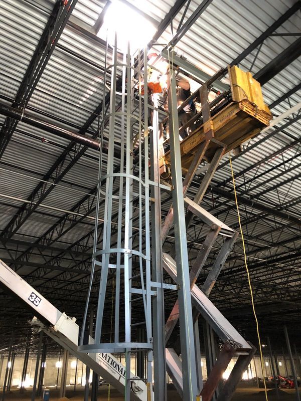 A man is working on a metal structure in a warehouse.