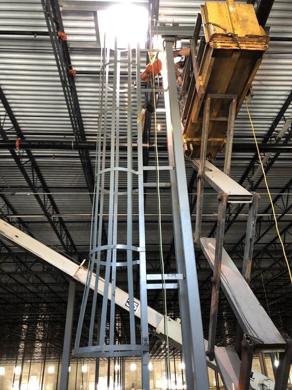 A man is standing on a ladder in a warehouse.