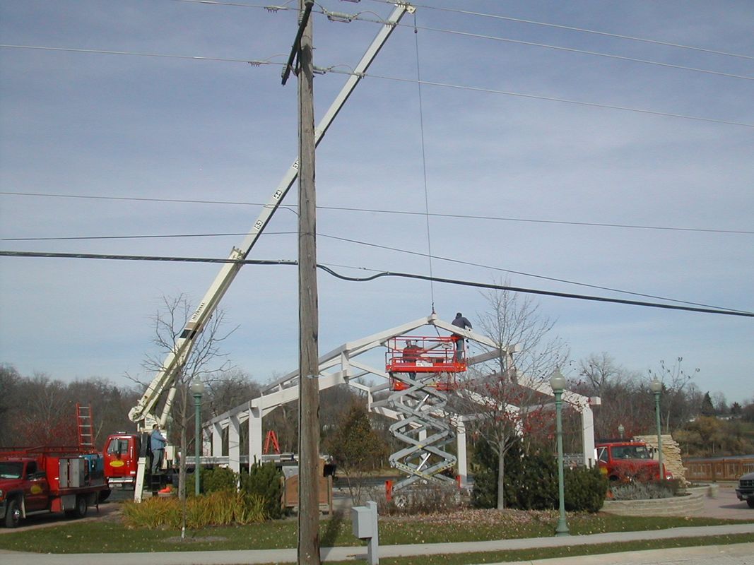 A red truck is parked next to a crane on a sunny day.