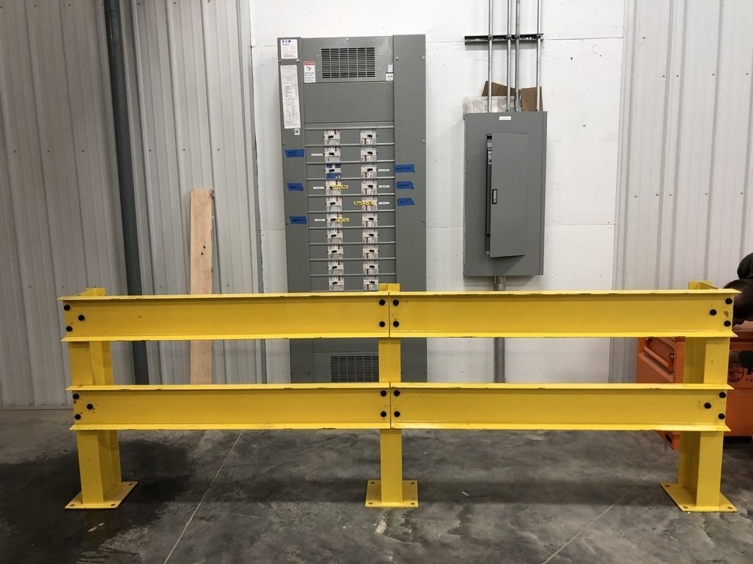A yellow barrier is sitting in front of a electrical panel.