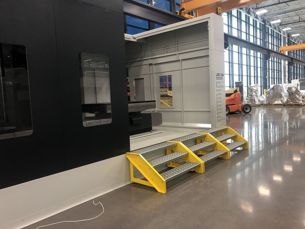 A machine is sitting in a factory with yellow steps.