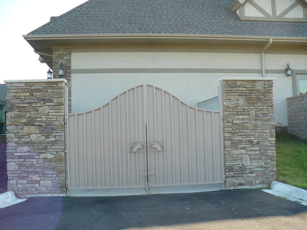 A house with a stone wall and a gate in front of it