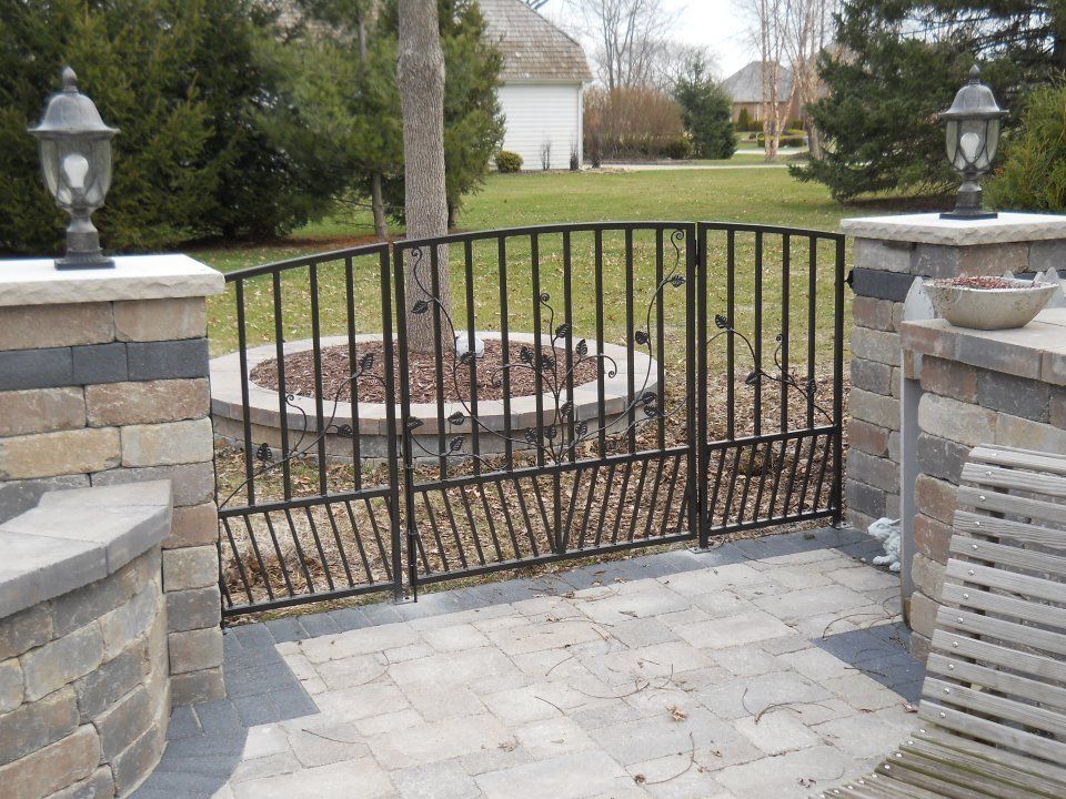 A wrought iron gate with a fire pit in the background