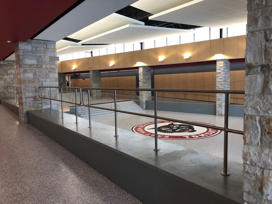 A long hallway with a railing and a logo on the floor.