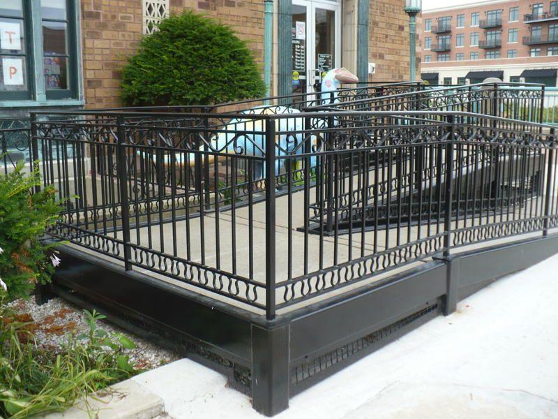 A ramp with a fence around it is leading to a building.