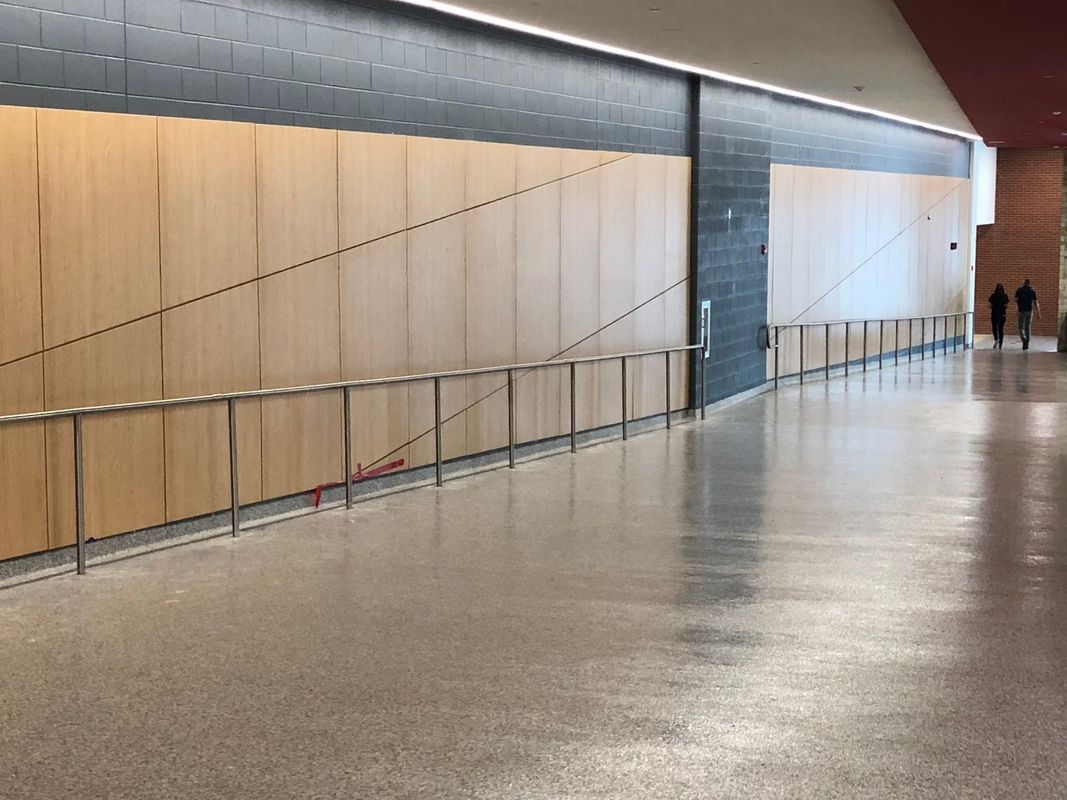 A long hallway with a wooden wall and a concrete floor