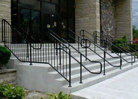 A set of stairs with a metal railing in front of a building.
