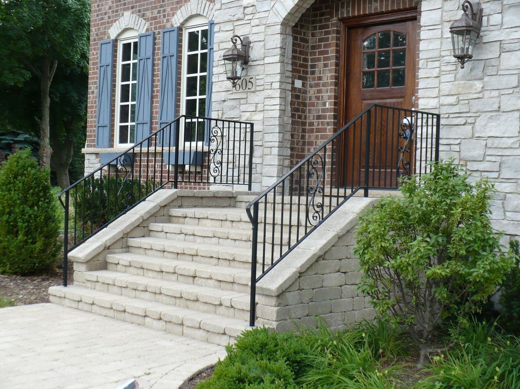 A brick house with stairs and a wrought iron railing