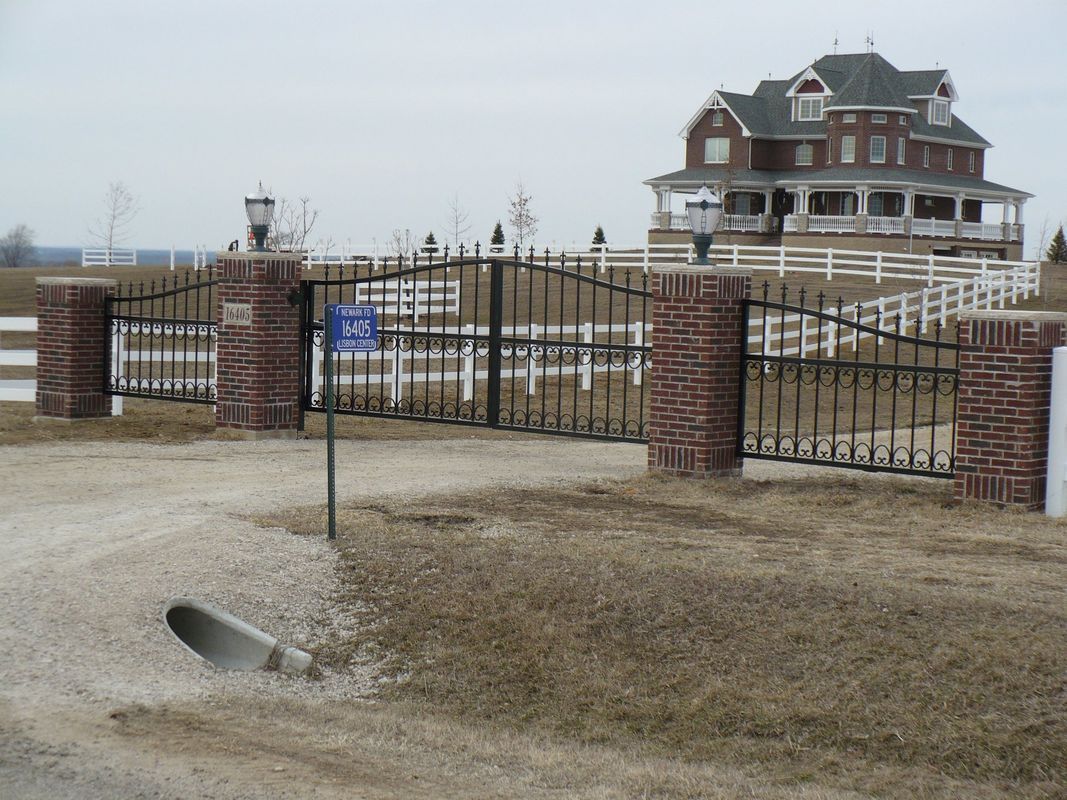 A large house is behind a wrought iron gate