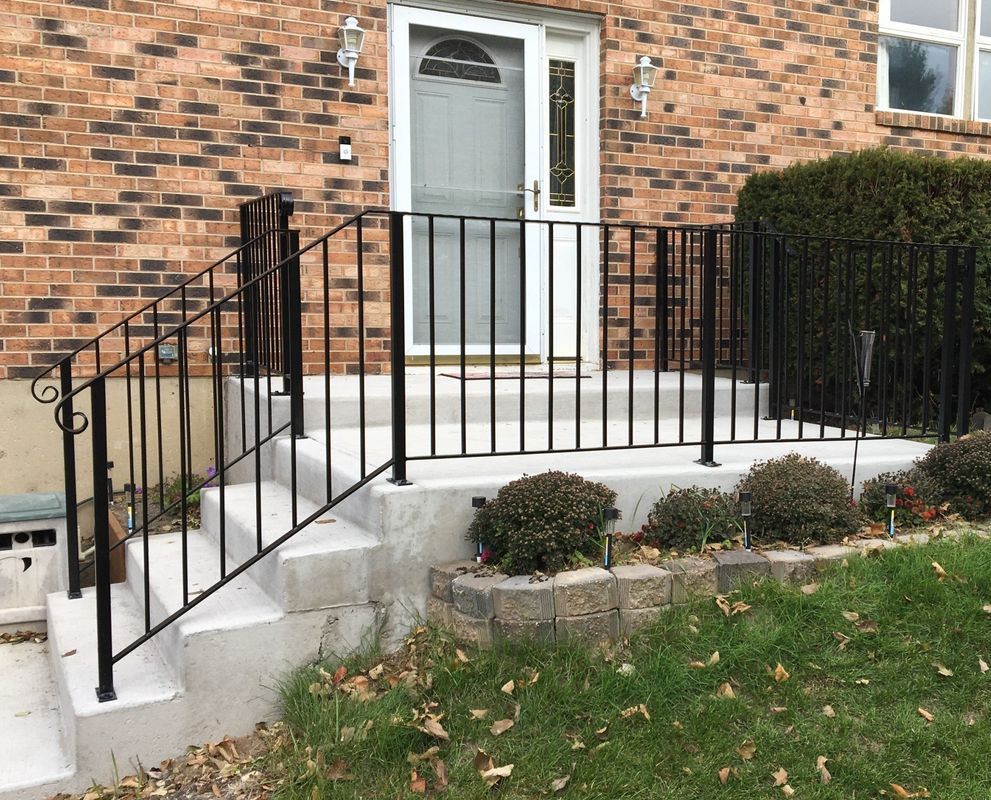 A brick house with a wrought iron railing and stairs