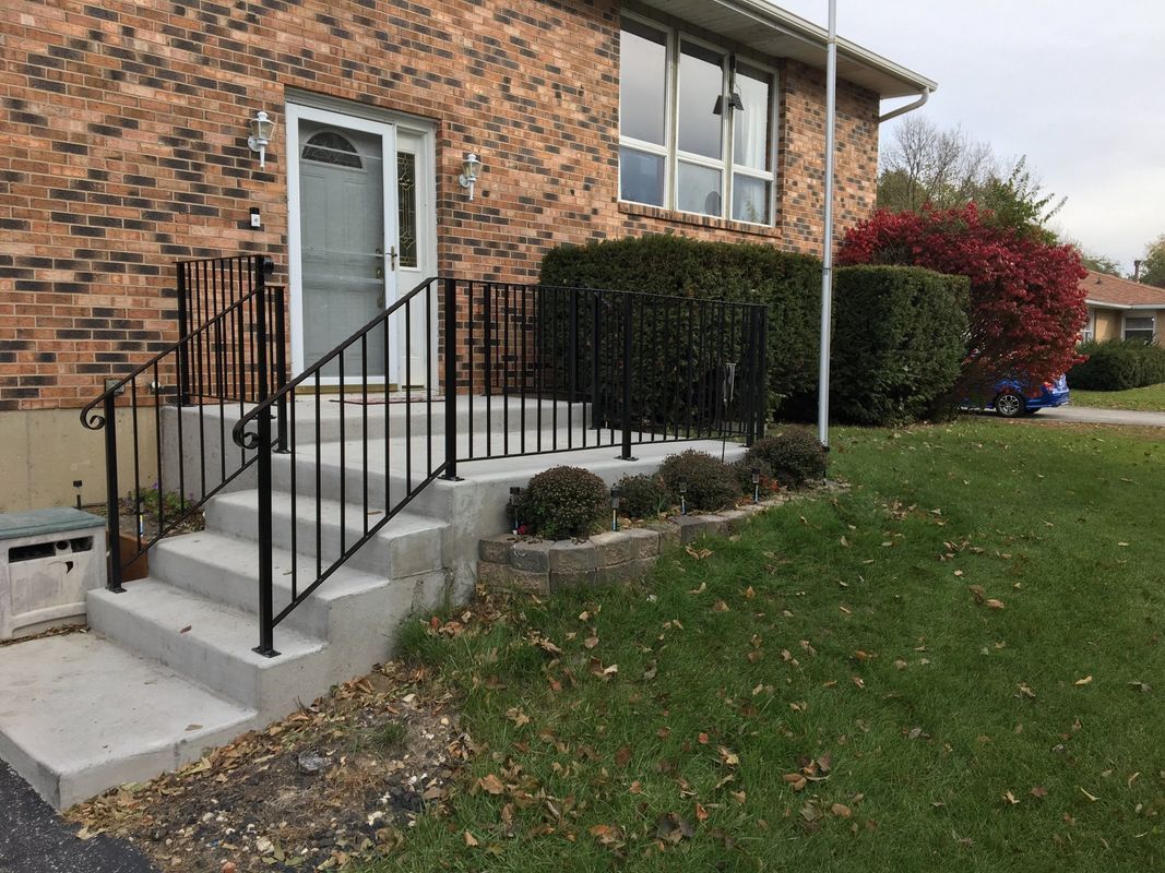 A brick house with stairs and a wrought iron railing