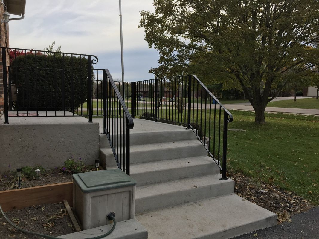A set of stairs leading up to a house with a metal railing.
