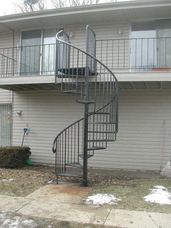 A spiral staircase leading up to a balcony on the side of a building