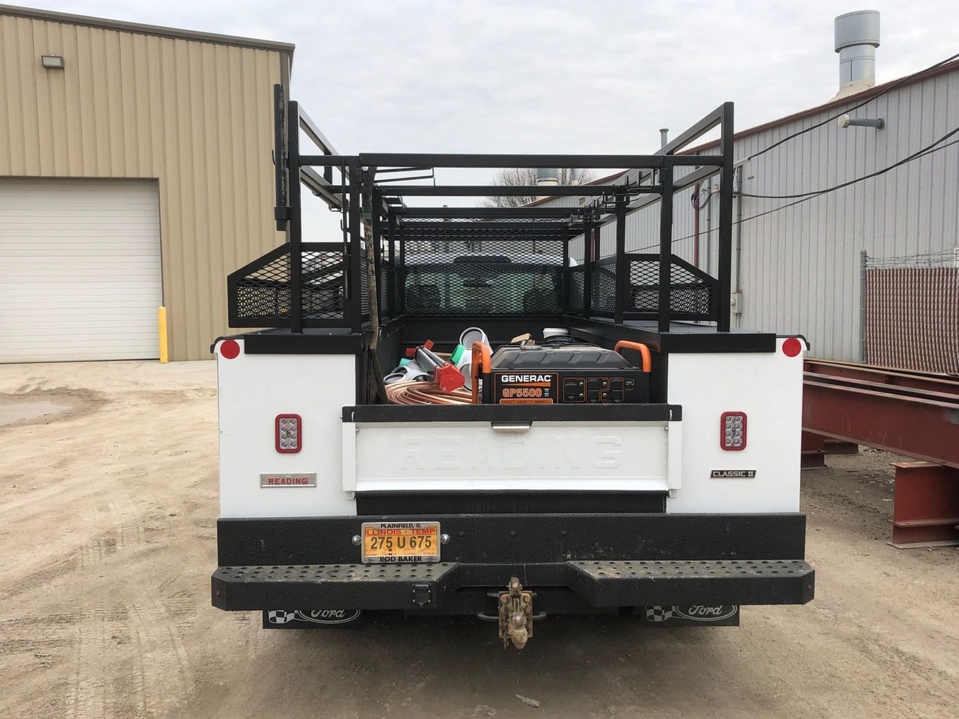 A white truck with a toolbox in the back is parked in front of a building.