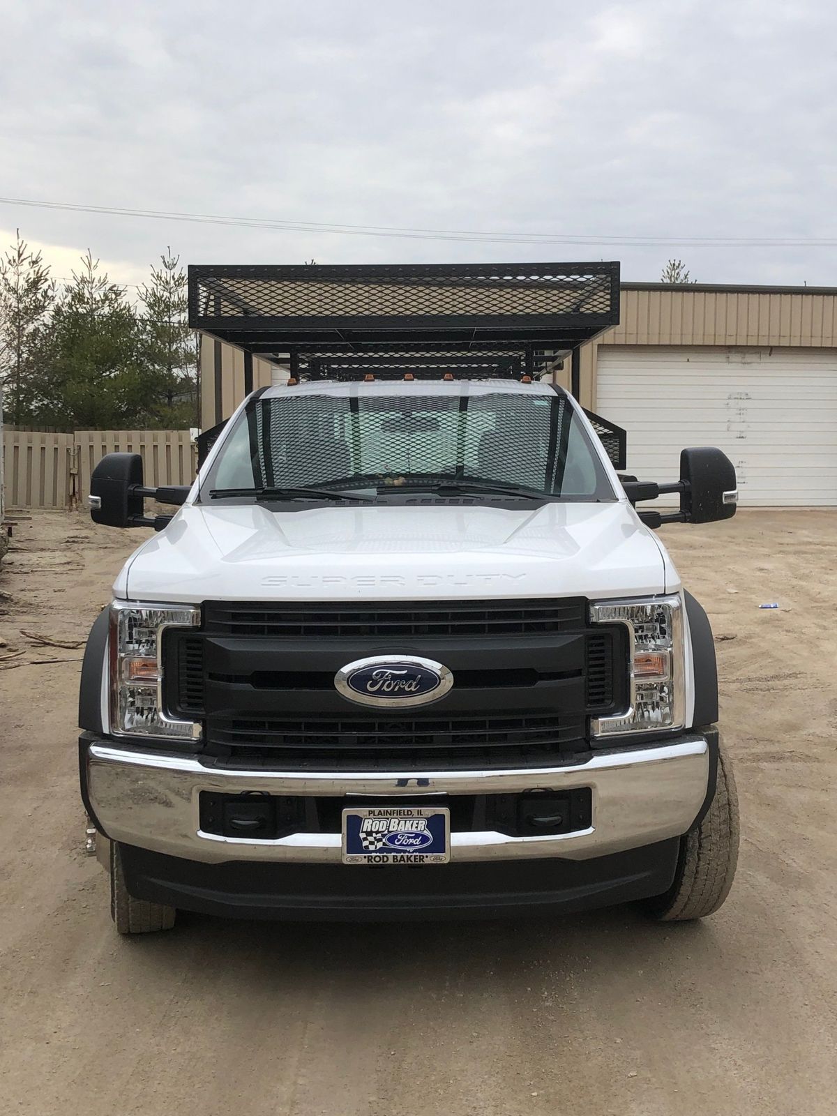 A white ford truck is parked in front of a garage.