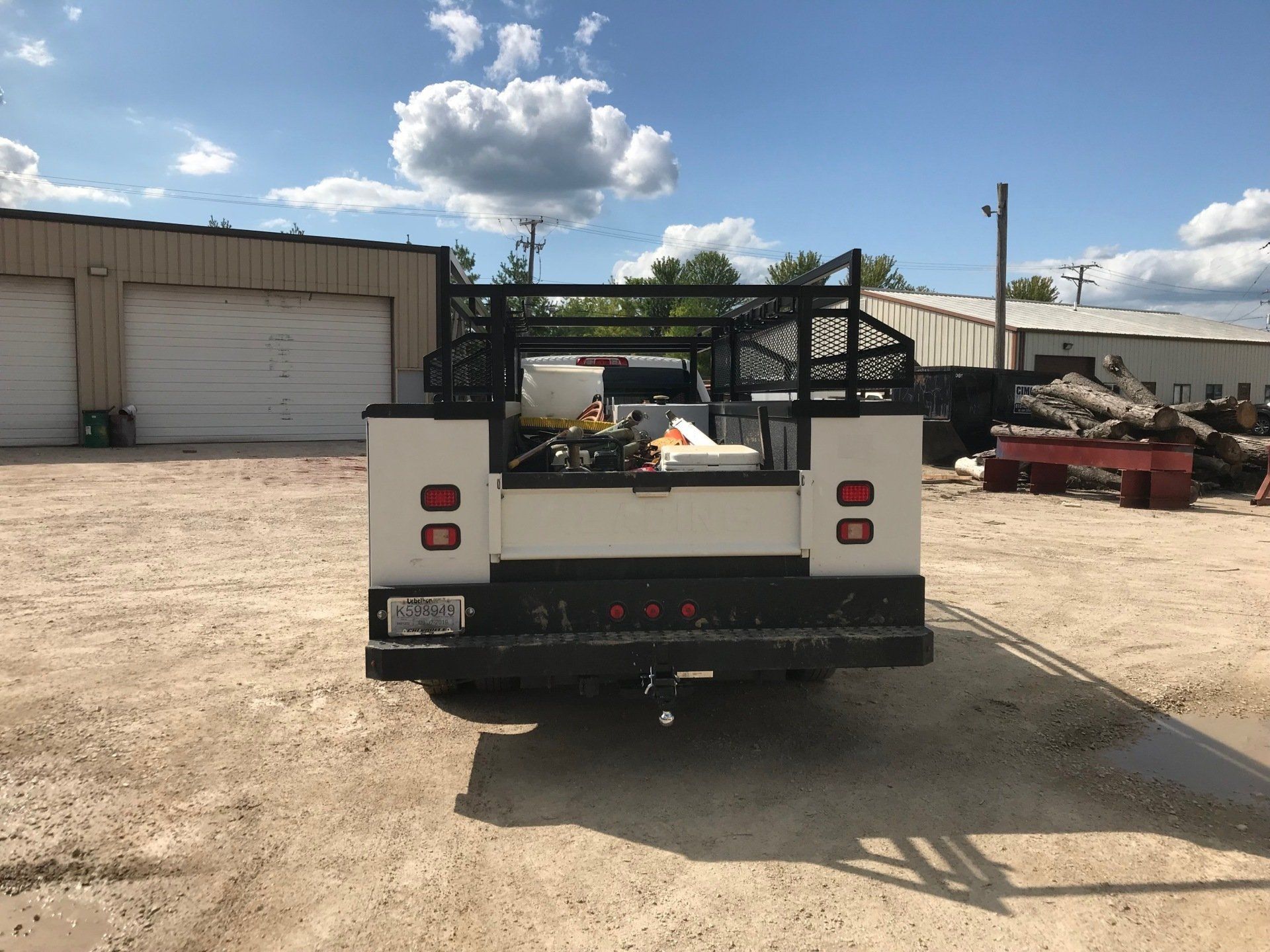 A white truck is parked in a dirt lot in front of a building.