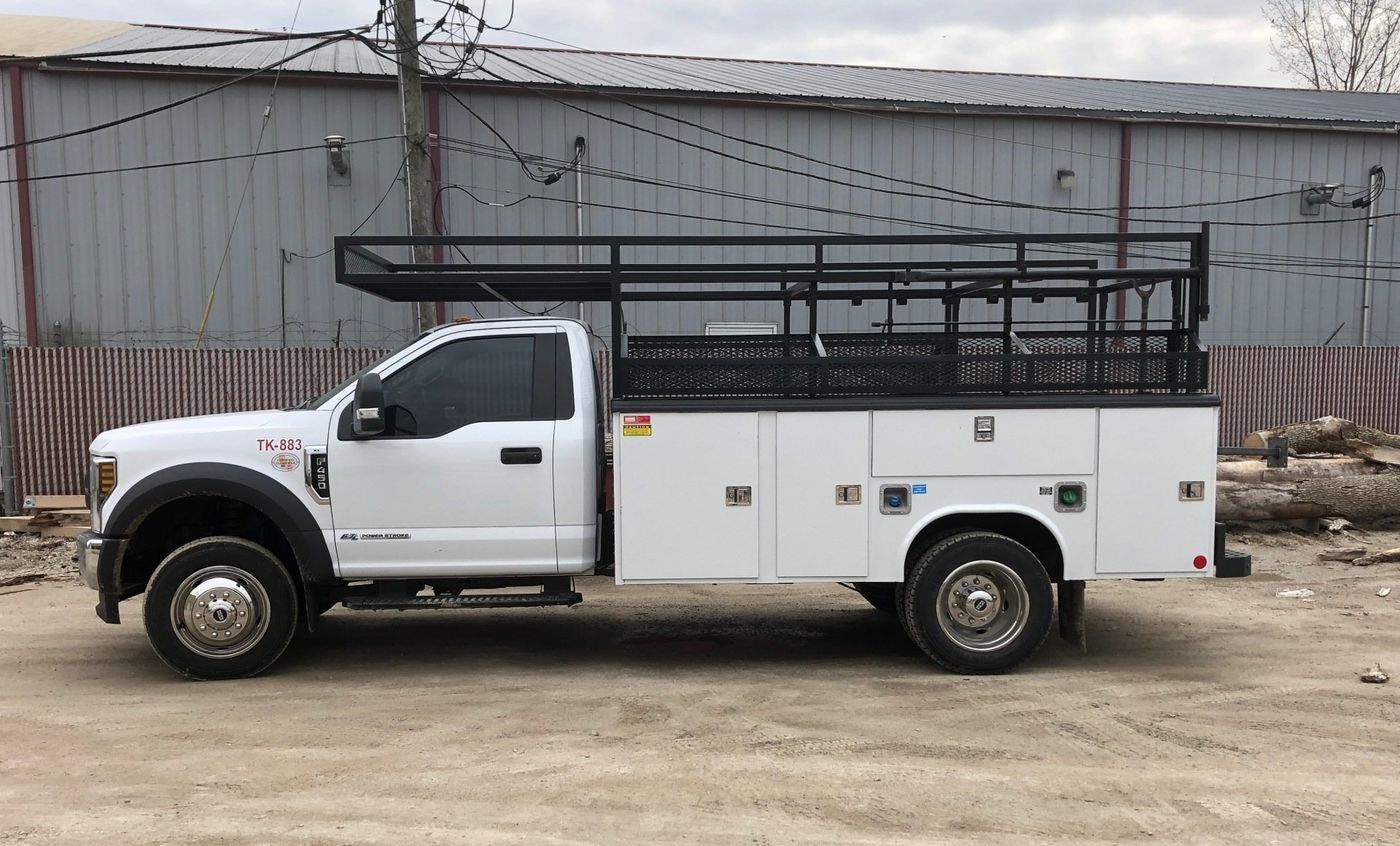 A white truck is parked in a dirt lot in front of a building.