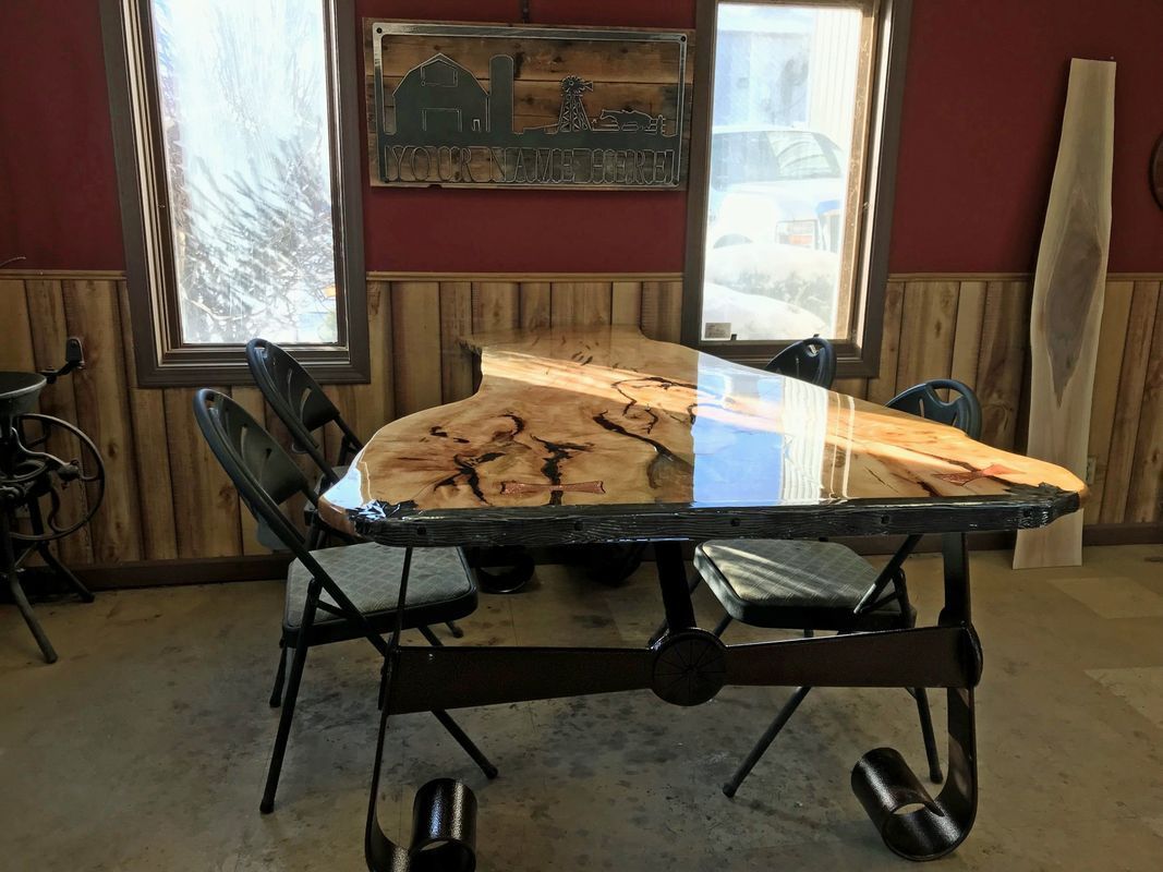 A wooden table with a glass top and chairs in a room.