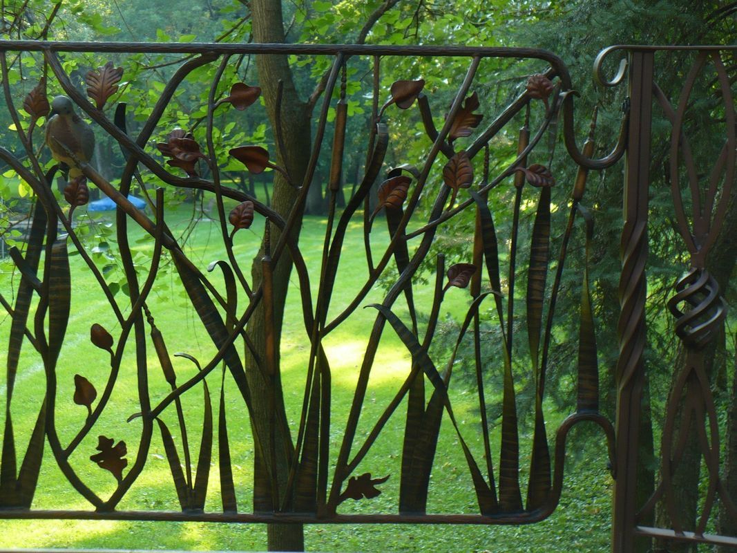 A wrought iron gate with trees and leaves on it