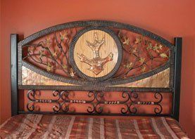 A bed with a wrought iron headboard with a deer head on it.