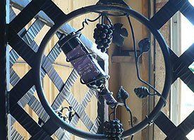 A bottle of wine is hanging from a vine in a wrought iron circle.