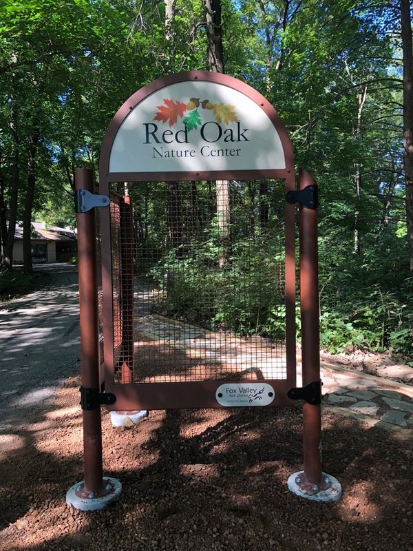 A gate with a sign that says red oak nature center