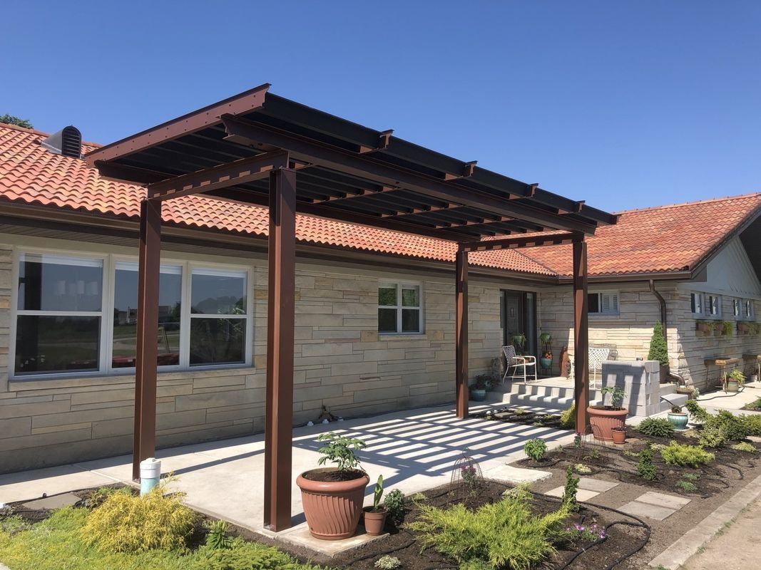 A house with a wooden pergola in front of it.